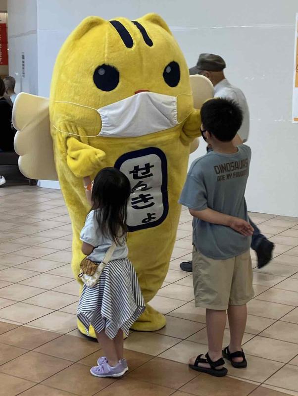 こどもたちと握手しているマスクをしためいすいくんの写真