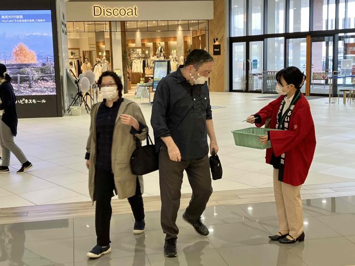 街頭啓発で絆創膏を配布している女性とその絆創膏を貰おうとしている男性の写真