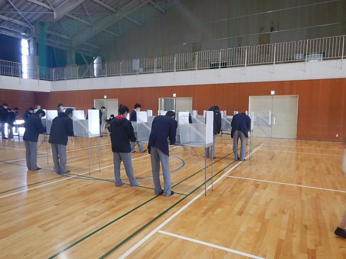 模擬投票で投票用紙に記入している高岡第一高等学校の生徒たちの写真