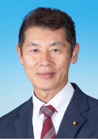 黒のスーツに白い線が入った赤色のネクタイを着けた男性の写真