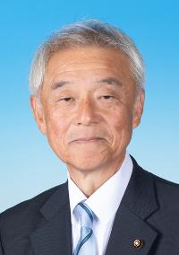 黒のスーツに青い線の入った水色のネクタイを着けた男性の写真