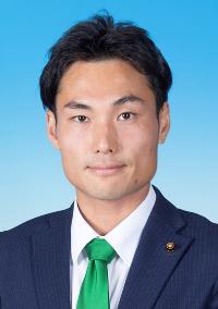 黒のスーツに緑色のネクタイを着けた男性の写真