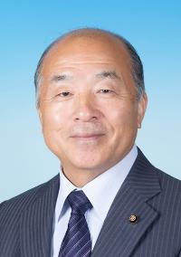 縦線の入った黒いスーツに白い線の入った紺色のネクタイを着けた男性の写真