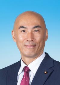 黒のスーツに模様の入った赤紫色のネクタイを着けた男性の写真