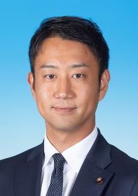 黒のスーツに模様の入った黒色のネクタイを着けた男性の写真