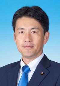 黒のスーツに青いネクタイを着けた男性の写真