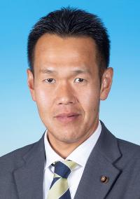 黒のスーツに紺色と黄色のネクタイを着けた男性の写真