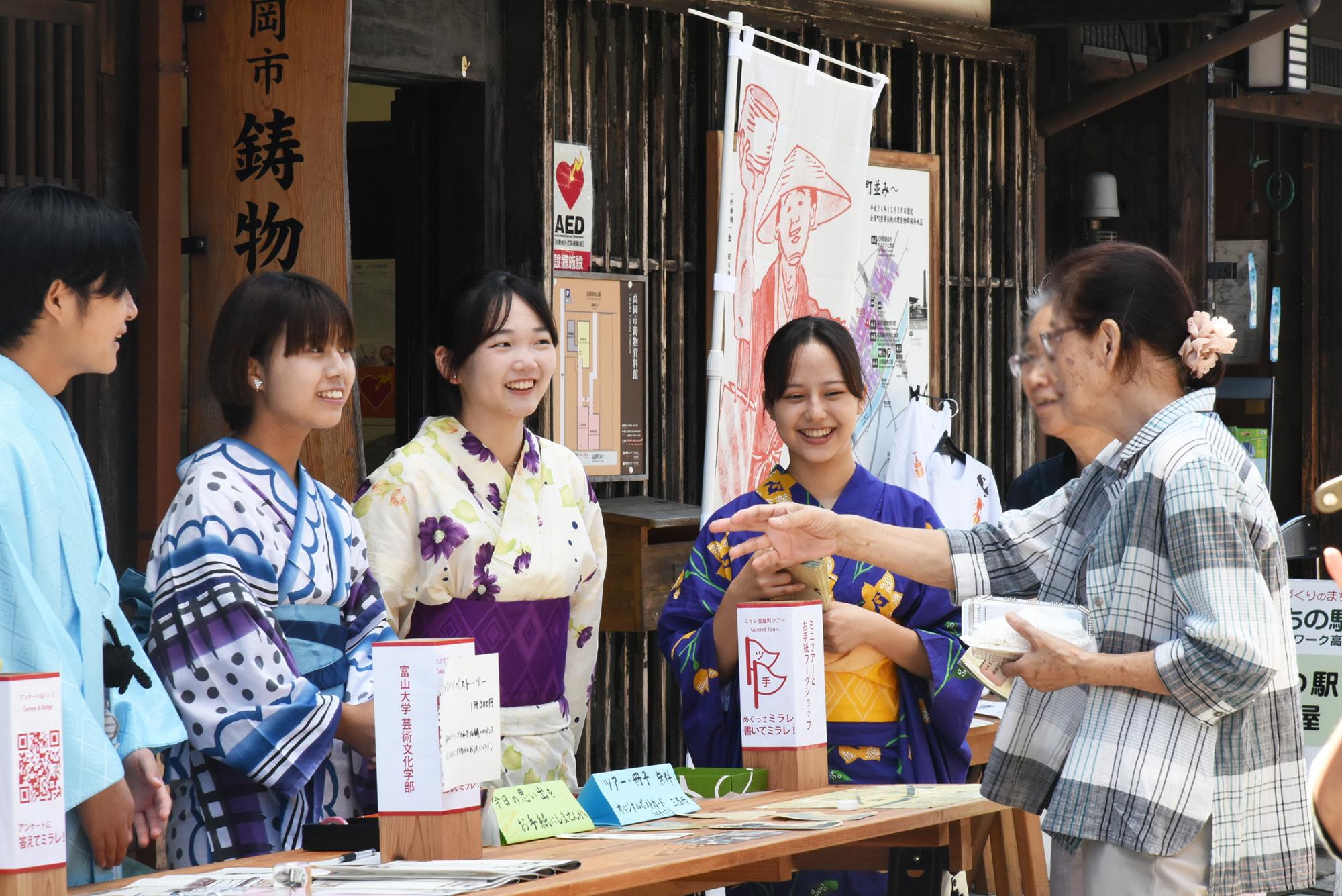 体験イベントで店員の女性の学生3人とお客さんが話している