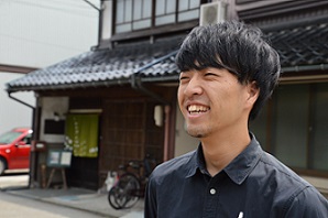 民家の前でインタビューに答える加納 亮介さんの写真