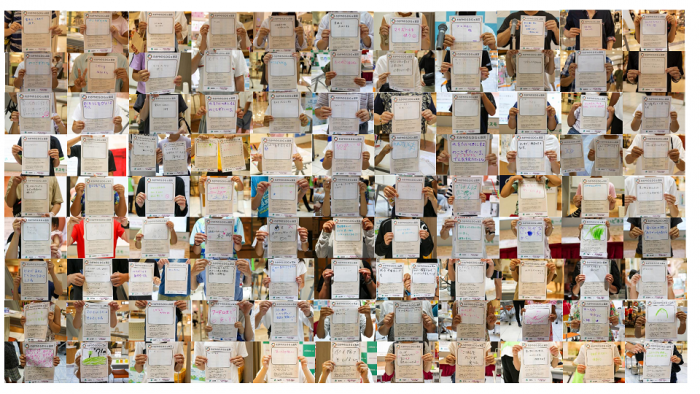 わがやのSDGs宣言で自分が行うSDGs宣言を紙に書いて胸の前に掲げているたくさんの人の写真