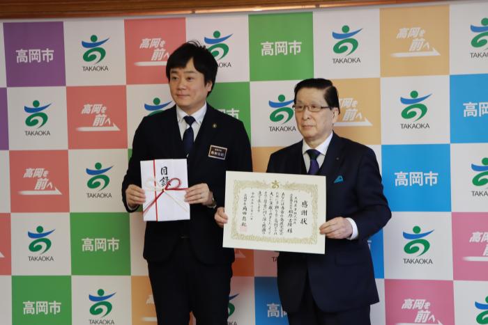 スーツを着た2人の男性が立って目録と感謝状を掲げている大同産業株式会社様の写真