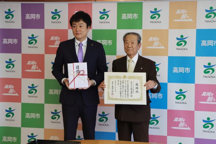 スーツを着た2人の男性が立って目録と感謝状を掲げている北陸予防医学協会様の写真