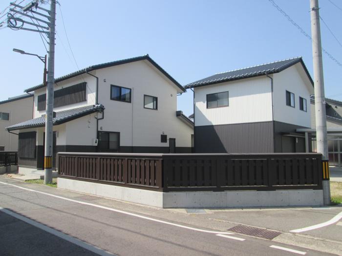 漆喰を意識した白い外壁の住宅と木製の大和塀が並ぶ写真