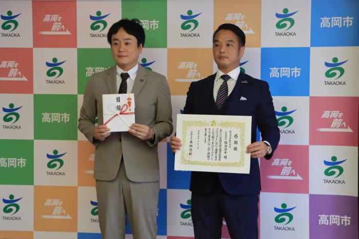 スーツを着た2人の男性が立って目録と感謝状を掲げている塩谷建設株式会社様の写真
