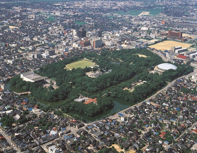 市街地の中にある濠と緑生い茂る高岡古城公園の空撮の写真