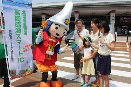 横断歩道上のマスコットキャラクターと男性1人と女性3人を写した写真