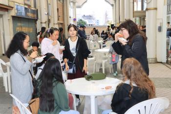 白いテーブルの前で立食をする女性たちの写真