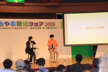 小嶋よしおさんと司会の女性によるトークショーの写真