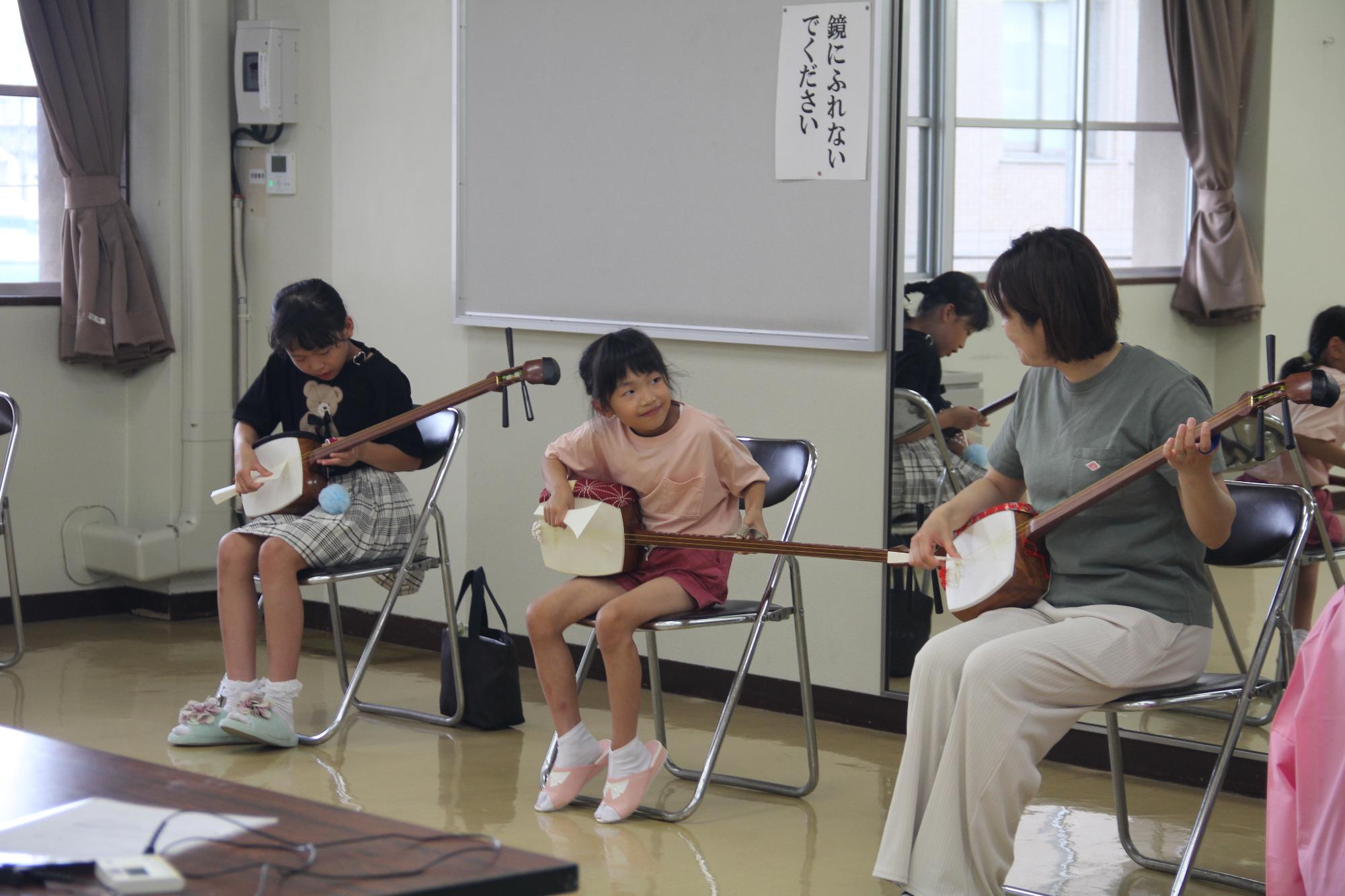 講師から三味線の弾き方を学ぶ子供たちの様子