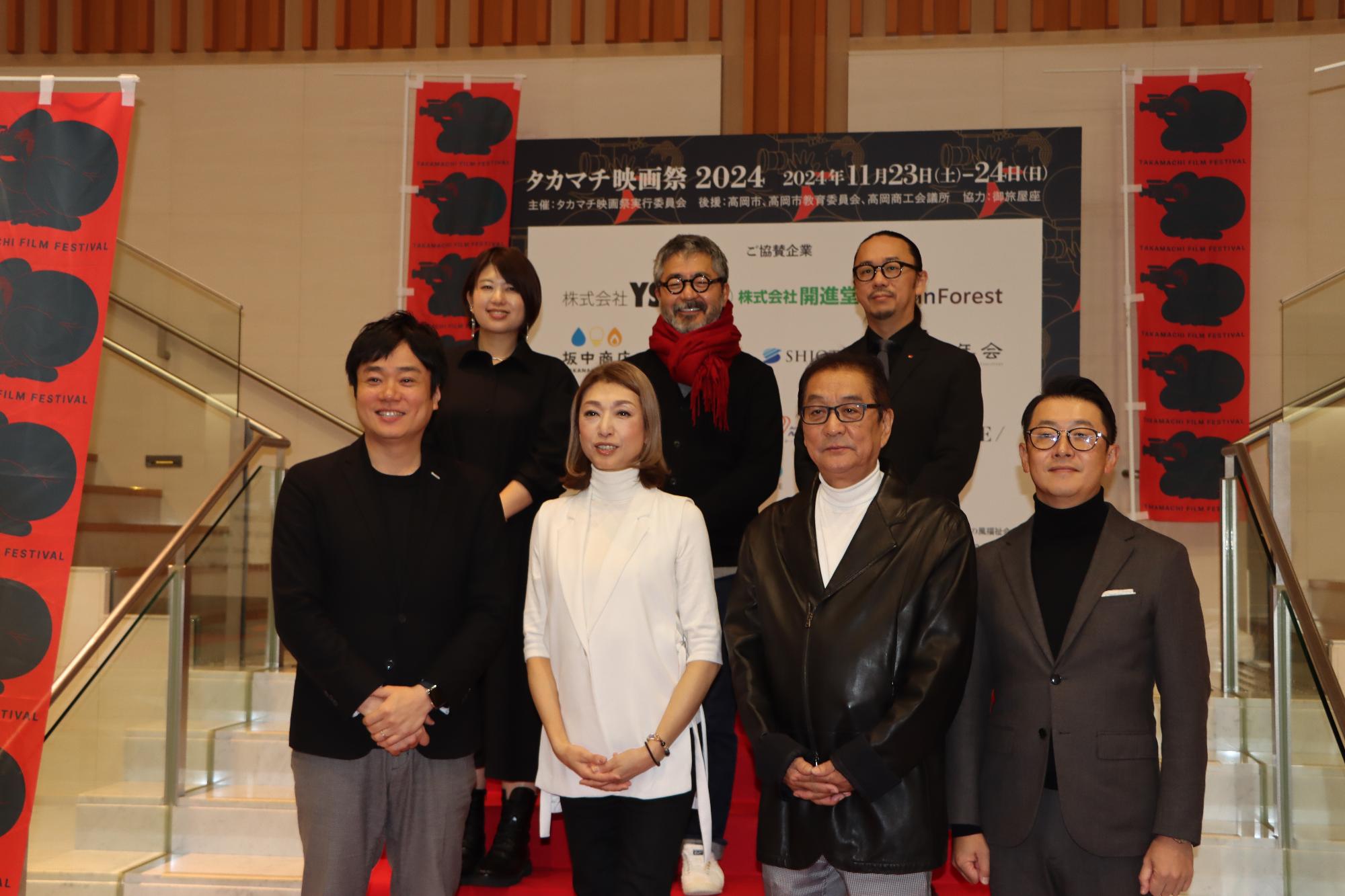 会場の会談で写真撮影をする出演者たちの様子