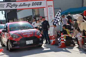 真っ赤なラリーカーが、Rally Challenge 2013 と書かれたアーチをくぐる写真