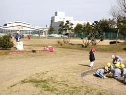 広々とした運動広場と、広場内にある砂場で遊ぶ子供達の写真