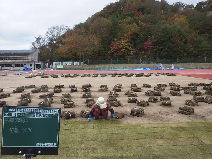 茶色い塊を並べている赤い作業着と白い帽子をかぶった人の写真