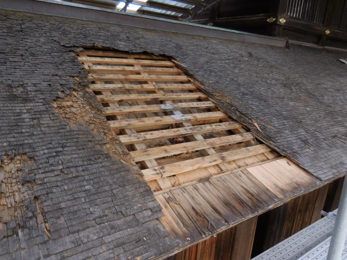 こけら板が撤去されて傷んだ下地が露出した、回廊付近の屋根の写真