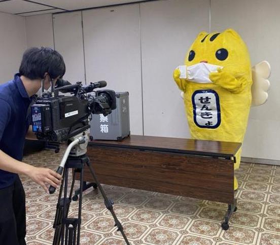 宣誓書を持っているマスクを付けためいすい君とカメラマンの写真
