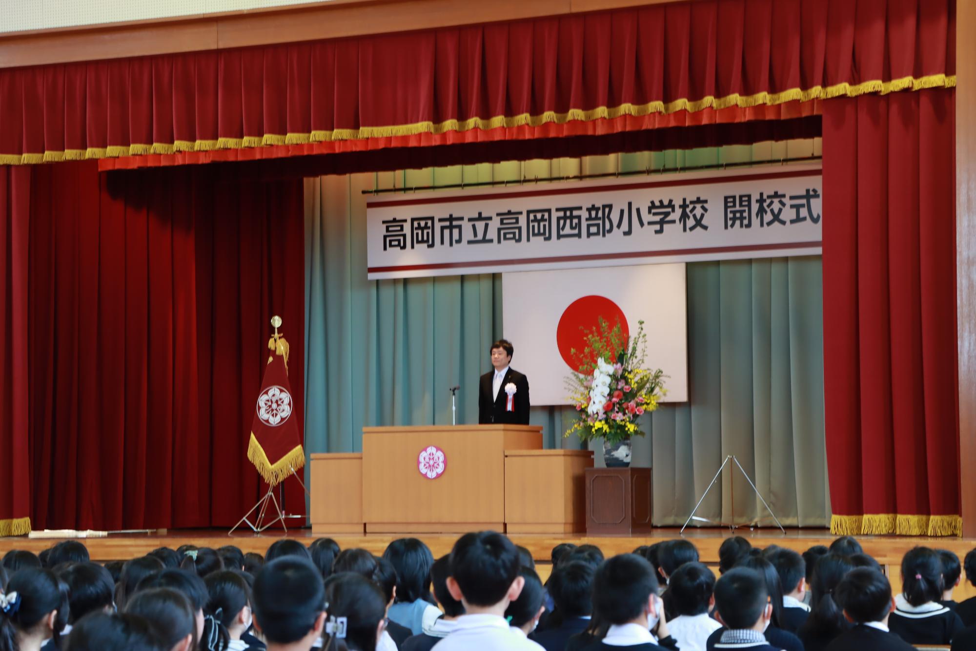 西部小学校の開校式で多くの生徒の前で祝辞を述べる市長
