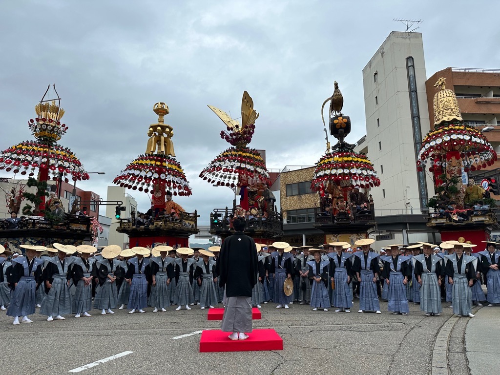 勢揃いした御車山と、その前で台に立ち、あいさつする袴すがたの市長